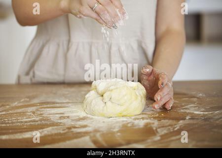 Crop Frau bereitet Teig am Tisch zu Hause Stockfoto