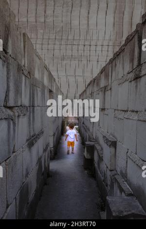 Kaukasisches junges Kind, das in einem Labyrinth läuft. Konzeptuelles Bild für gefährliche Situationen in der Kindheit. Stockfoto