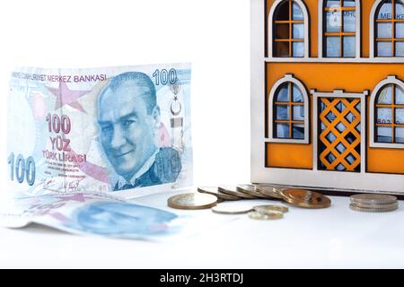 Sparkonzept für Unternehmen, Finanzen und Investitionen. Holzhausmoneybox, türkische Banknoten und Münzen auf isoliertem weißem Hintergrund. Stockfoto