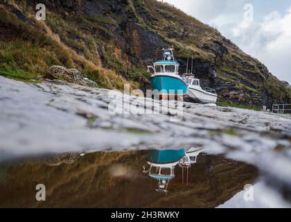 Alte Fischerboote in Trockendock Felswand Hafen vertäut schöne Landschaft im Wasser reflektiert. Wunderschöne Farben und dramatischer Himmel. Stockfoto