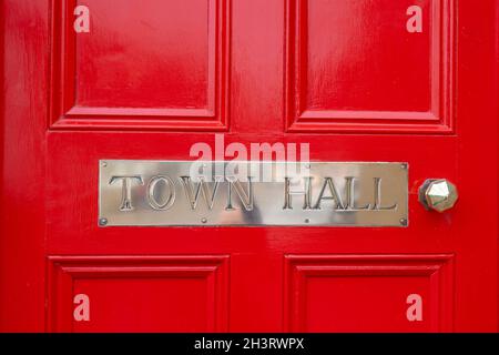 Rathaus silbernes Metallschild. Schild aus poliertem Chromstahl auf hellroter Holztür, glänzender und sauberer Edelstahlgriff. Rathaus mit Großbuchstaben Stockfoto