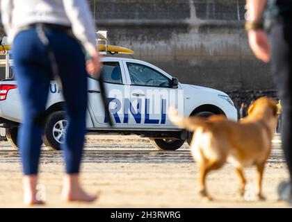 23.10.2021 Newquay, Cornwall. Außerhalb des Fokus Urlauber RNLI Rettungsboot Allradantrieb 4x4 geparkt am Sandstrand beobachten Surfer sicher zu gewährleisten Stockfoto