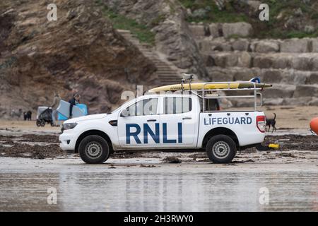 23.10.2021 Newquay, Cornwall. Außerhalb des Fokus Urlauber RNLI Rettungsboot Allradantrieb 4x4 geparkt am Sandstrand beobachten Surfer sicher zu gewährleisten Stockfoto