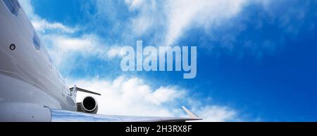 Teil eines modernen Privatjet-Flugzeugs mit einem Heck und Flügel über dem Himmel Hintergrund, Panorama-Layout mit Platz für Text Stockfoto