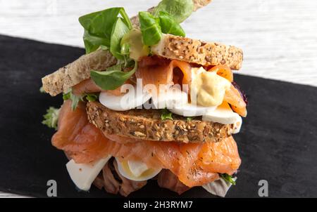 Köstliches Müsli-Sandwich mit geräuchertem Lachs und frischem Käsekernbrot und Müsli. Isoliertes Bild Stockfoto