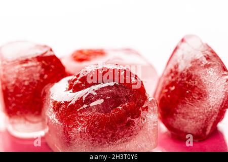 Himbeer-Eiswürfel auf rosa glänzenden Hintergrund Stockfoto