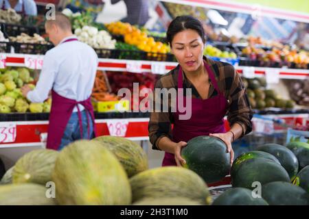 Weibliche Greengrocery Besitzerin, die Obst und Gemüse für den Verkauf an der Theke vorbereitet Stockfoto