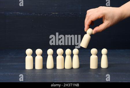 Die weibliche Hand hält eine Holzfigur, die aus der Menge ausgewählt wurde Stockfoto