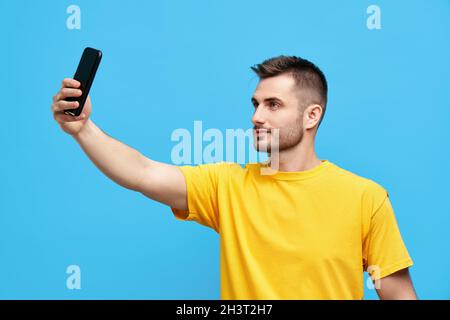 Hübscher junger Mann, der Selfie über blauem Hintergrundfvg nimmt Stockfoto