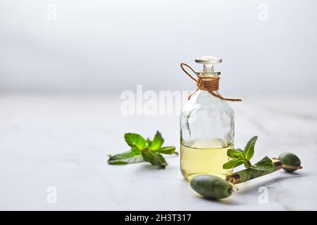 Flasche ätherisches Öl aus Minze und grünen Blättern und Jade-Massagerolle für das Gesicht. Natürliche Bio-Inhaltsstoffe für Kosmetika Stockfoto