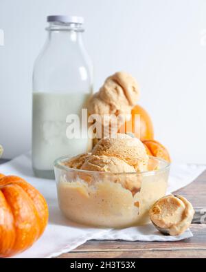 Schüssel mit Kürbis-Eis mit Kürbis, Schaufel, Kegel und einer Glasflasche mit Creme Stockfoto