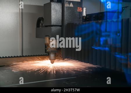 Funken fliegen aus dem Maschinenkopf für Metall verarbeitende Lasermetalle auf metallurgischem Werkshintergrund. Fertigung von Fertigteilen für Stockfoto