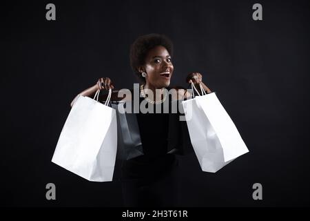 Afroamerikanische Frau hält schwarze Einkaufstaschen. Verkauf und Rabatte auf Markt und Black Friday Konzept. Stockfoto