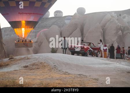 GOREME, TÜRKEI - 5. AUGUST 2021: Morgens versammeln sich Menschen mit teuren Oldtimern und gut aussehender Kleidung, um Selfies und Fotos zu machen Stockfoto