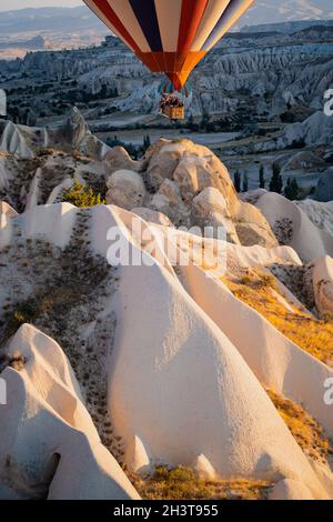 GOREME, TÜRKEI - 3. AUGUST 2021: Nahaufnahme von bunten Heißluftballons mit Korb voller Touristen, die sehr nah am Boden über den Kappadoki fliegen Stockfoto