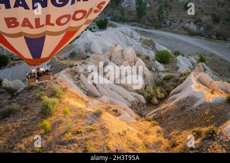 GOREME, TÜRKEI - 3. AUGUST 2021: Ansicht von oben Nahaufnahme eines bunten Heißluftballons mit Korb voller Touristen, die sehr nah am Boden über dem C fliegen Stockfoto