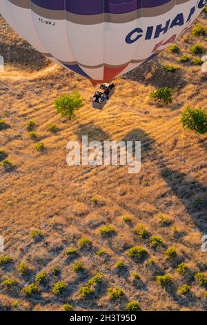 GOREME, TÜRKEI - 3. AUGUST 2021: Ansicht von oben Nahaufnahme eines bunten Heißluftballons mit Korb voller Touristen, die sehr nah am Boden fliegen und sich vorbereiten Stockfoto