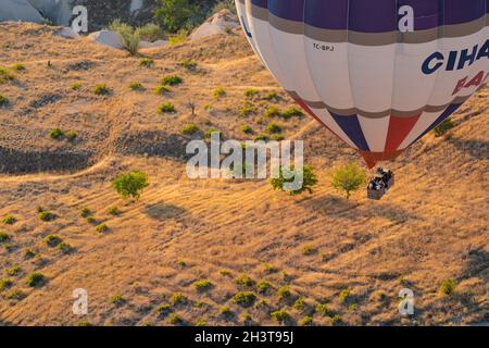 GOREME, TÜRKEI - 3. AUGUST 2021: Ansicht von oben Nahaufnahme eines bunten Heißluftballons mit Korb voller Touristen, die sehr nah am Boden fliegen und sich vorbereiten Stockfoto