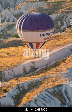 GOREME, TÜRKEI - 3. AUGUST 2021: Ansicht von oben Nahaufnahme eines bunten Heißluftballons mit Korb voller Touristen, die sehr nah am Boden über dem C fliegen Stockfoto