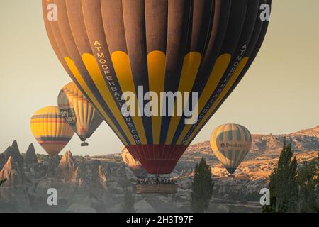 GOREME, TÜRKEI - 3. AUGUST 2021: Nahaufnahme von bunten Heißluftballons mit Korb voller Touristen, die sehr nah am Boden über den Kappadoki fliegen Stockfoto