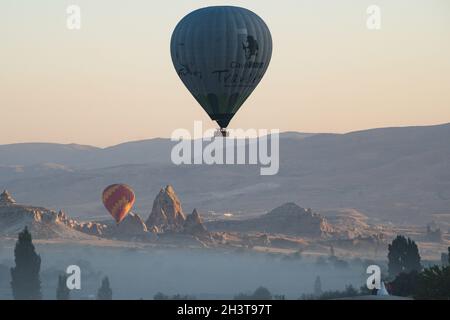 GOREME, TÜRKEI - 3. AUGUST 2021: Bunte Heißluftballons fliegen im Morgenlicht über das Kappadokien-Tal Stockfoto