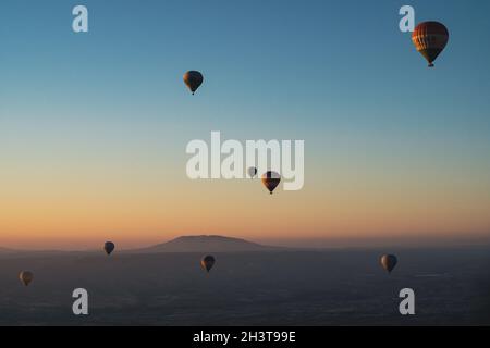 GOREME, TÜRKEI - 3. AUGUST 2021: Bunte Heißluftballons fliegen im Morgenlicht über das Kappadokien-Tal Stockfoto