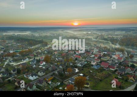 Eine kleine Provinzstadt. Eine Rauchwolke hängt über den Gebäuden, Smog aus den Schornsteinen. Das Foto wurde mit einer Drohne aufgenommen. Stockfoto