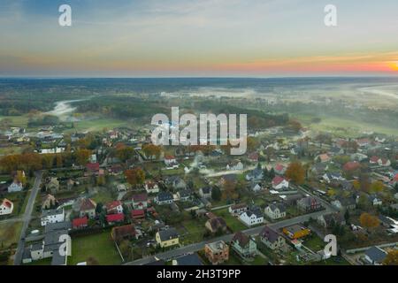 Eine kleine Provinzstadt. Eine Rauchwolke hängt über den Gebäuden, Smog aus den Schornsteinen. Das Foto wurde mit einer Drohne aufgenommen. Stockfoto