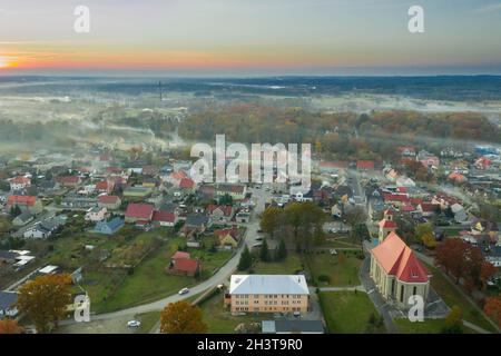 Eine kleine Provinzstadt. Eine Rauchwolke hängt über den Gebäuden, Smog aus den Schornsteinen. Das Foto wurde mit einer Drohne aufgenommen. Stockfoto