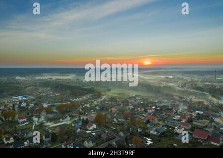 Eine kleine Provinzstadt. Eine Rauchwolke hängt über den Gebäuden, Smog aus den Schornsteinen. Das Foto wurde mit einer Drohne aufgenommen. Stockfoto