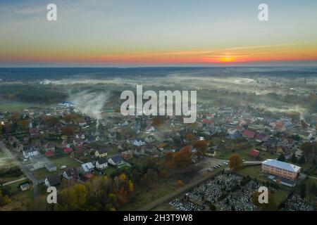 Eine kleine Provinzstadt. Eine Rauchwolke hängt über den Gebäuden, Smog aus den Schornsteinen. Das Foto wurde mit einer Drohne aufgenommen. Stockfoto