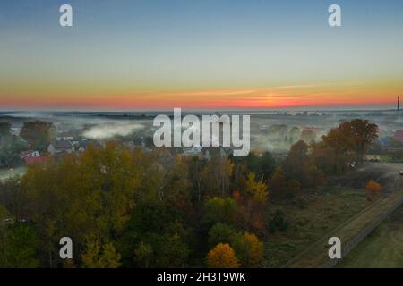 Eine kleine Provinzstadt. Eine Rauchwolke hängt über den Gebäuden, Smog aus den Schornsteinen. Das Foto wurde mit einer Drohne aufgenommen. Stockfoto