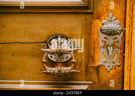 Original antike Türgriff-Ring in Vergoldung auf einer Holztür mit Schlüsselloch. Stockfoto