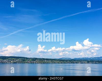 Idyllische Schweizer Landschaft, Blick auf den Zürichsee in Wollerau, Kanton Schwyz in der Schweiz, Zürichsee, Berge, blaues Wasser, Himmel Stockfoto