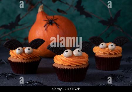 Halloween Treat - Helle süße Kuchen in Form von Fledermäusen auf einem grünen Hintergrund mit Dekor. Stockfoto