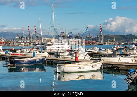 Großer Hafen mit vielen Booten, Kräne und Containerschiffen. Internationaler Hafen im Golf von La Spezia an einem sonnigen Wintertag. Ligurien, Italien. Stockfoto