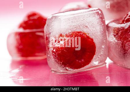 Himbeer-Eiswürfel auf rosa glänzenden Hintergrund Stockfoto