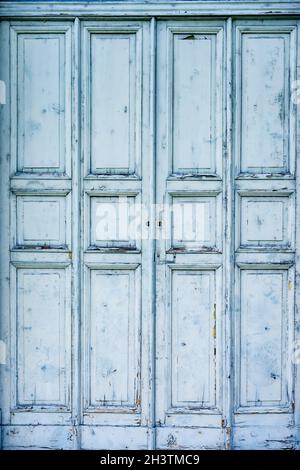 Hölzerne alte Tür von blauer Farbe, mit geschnitzten Rechtecken und Quadraten. Stockfoto