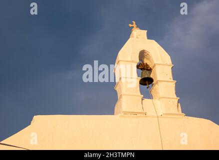 Glockenturm der weißen orthodoxen Kirche. Weiß getünchte Wand vor blauem Himmel Hintergrund. Mykonos Insel, Kykladen Griechenland. Stockfoto