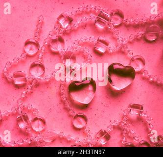 Transparente Herzen und Perlen auf Marmor in rosa Ton. Perfekte Valentinstag Grußkarte Hintergrund. Stockfoto