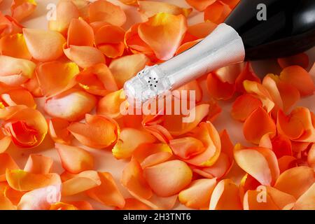 Champagner-Flasche in orange Rosenblüten aus nächster Nähe Stockfoto