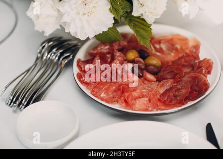 Verschiedene Aufschnitte auf einem Teller mit weißen Blumen auf dem Tisch Stockfoto