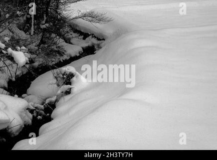 Ein gewundener Abflussgraben am Boden schneebedeckter Felder, die Ouchi-Juku umgeben – eine alte Poststadt in der Präfektur Fukushima, Japan. Stockfoto