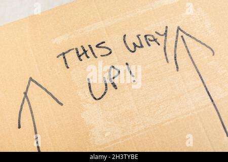 Handschriftliche „This Way Up“-Anweisungen zur Paketbearbeitung auf der Seite eines Pappkartons. Bei Paketsendungen können Pakete per Post oder per Kurier versendet werden Stockfoto