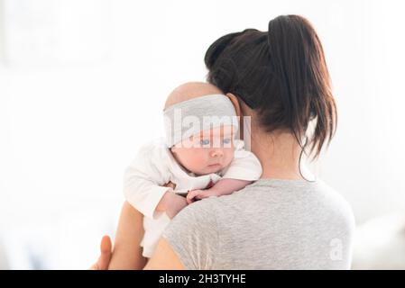 Mutter hält neugeborenes Baby in einem hellen Raum Stockfoto