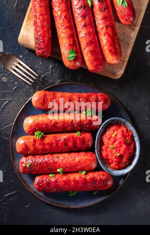Gegrillte Würstchen mit Ketchup, darüber liegende flache Lage auf schwarzem Hintergrund Stockfoto