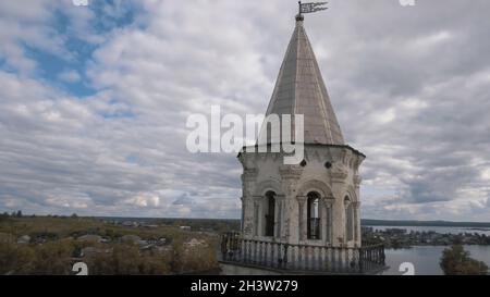 Landschaft mit einem alten weißen Turm umgeben von Kleinstadt und Wald auf blau bewölktem Himmel Hintergrund. Antenne des verlassenen alten Turms, ar Stockfoto
