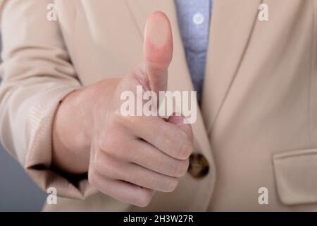 Mittelteil der kaukasischen Geschäftsfrau berührt virtuelle Schnittstelle auf grauem Hintergrund Stockfoto