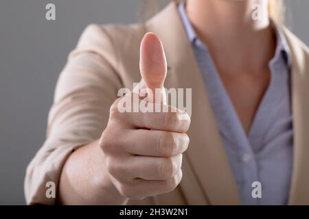 Mittelteil der kaukasischen Geschäftsfrau berührt virtuelle Schnittstelle auf grauem Hintergrund Stockfoto