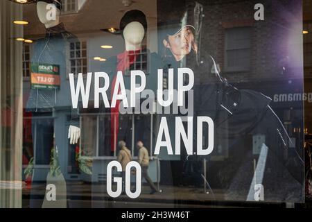 Wintermode-Shop in der High Street mit Text auf dem Fenster, „Wrap Up and Go“. Fensteranzeige. Stockfoto